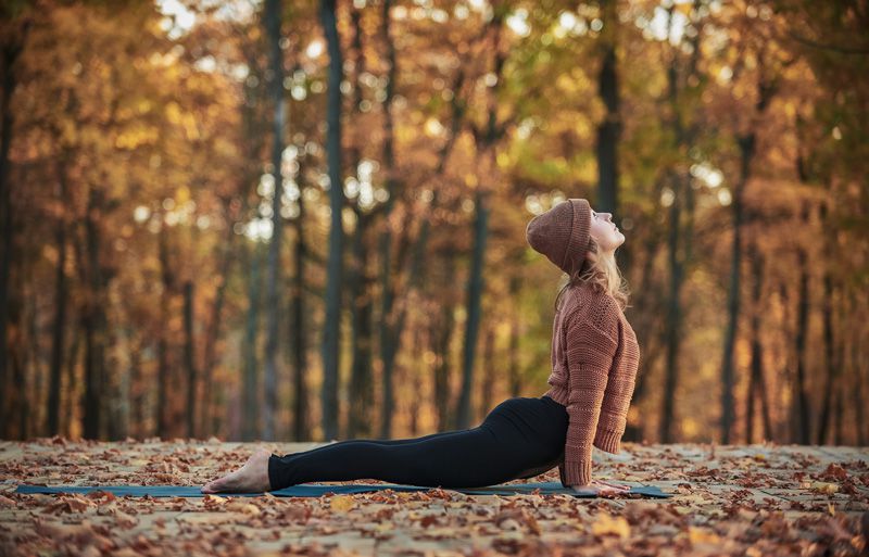 Eine Frau macht eine Yogaübung im herbstlichen Wald